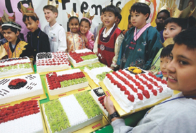 Children from various countries show their national flag-shaped cakes.