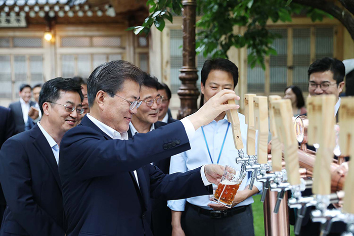 President Moon Jae-in (second from left) fills a glass of beer during a meeting with business leaders at Sangchunjae Hall in Cheong Wa Dae on July 27. All the beer served was hand-brewed by small- and medium-sized firms.