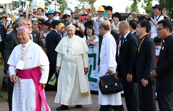 Pope Francis smiles as he greets the believers in the crowd.
