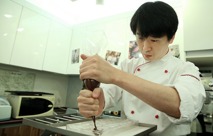 Chocolatier Hong Gyoung-chun fills an empty mold with chocolate.