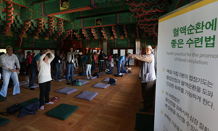 Visitors to Donguibogamchon Village take part in some exercises known to promote blood circulation.
