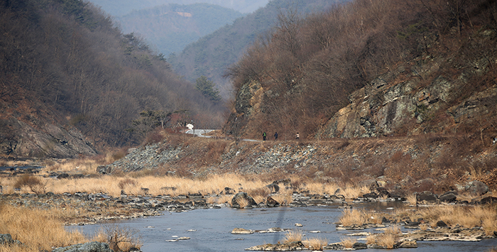 Pictured is a section Jinmoe Village in Imsil County, Jeollabuk-do. A group of cyclists zip along the bike trail along the Seomjingang River, taking in the end-of-winter landscape. 