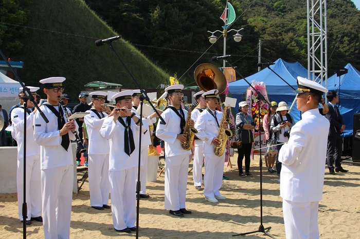 (Top) Sailor Kim Seung-jin takes a photo with Dangjin citizens who gathered at the port to celebrate his return. (Bottom) A naval band celebrates his safe return.