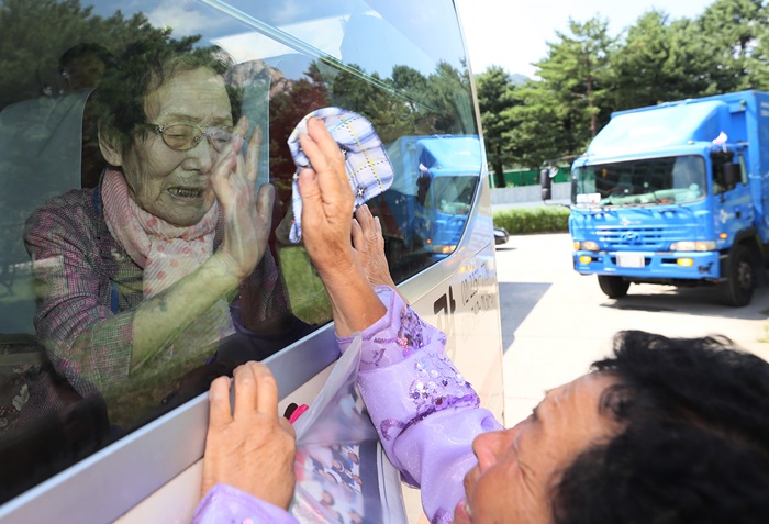 On Aug. 22, the last day of the 21st inter-Korean family reunions, Han Shin-ja from South Korea touches the bus window in her attempt to feel her North Korean daughter’s hand as she bids farewell on the bus.