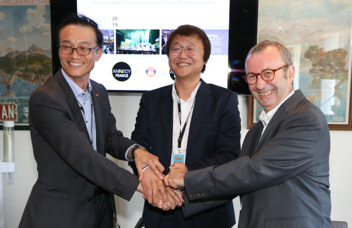 SK Broadband executive Yoon Sang-chul (left), Seoul Business Agency CEO Joo Hyeong Cheol (center) and Annecy International Animated Film Festival director Patrick Eveno pose for a photo after signing an MOU to hold the festival in Seoul, in Annecy, France, on June 13. (Seoul Business Agency)