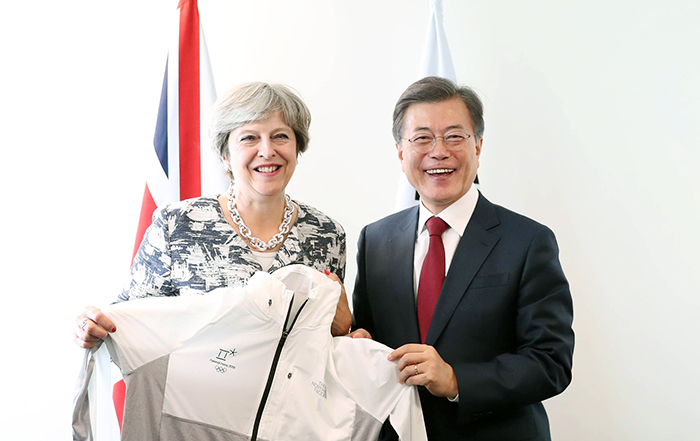 The U.K.'s Prime Minister Theresa May (left) receives a PyeongChang 2018 Olympic and Paralympic Winter Games uniform from President Moon Jae-in after their meeting at U.N. headquarters in New York on Sept. 19. (Cheong Wa Dae)