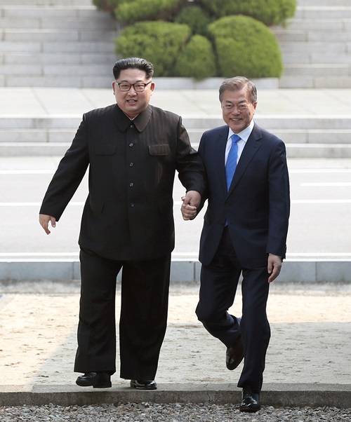 President Moon (right) on April 27 crosses the Military Demarcation Line (MDL) separating the two Koreas with North Korean leader Kim Jong Un, at the truce village of Panmunjeom before their first summit. (2018 Inter-Korean Summit Press Corps)