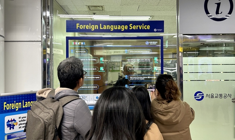 Seoul Metro will install its artificial intelligence-based simultaneous interpretation service to 11 more stations. Shown are foreign visitors in December last year using the system at Myeongdong Station. (Choi Jin-woo)