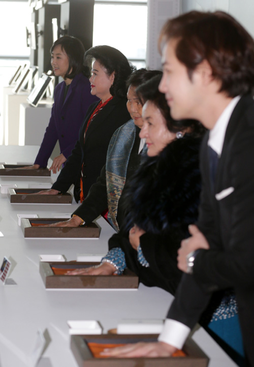 First ladies from Cambodia, Laos and Malaysia make a hand print together with actor Jang Keun-suk (right) at the Busan Cinema Center in Busan on December 12. 