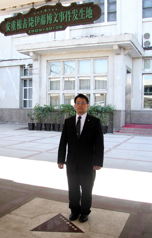 An Do-yong, great-grandson of independence activist An Jung-geun, stands at the memorial plaque on May 9 on the spot where his great-grandfather fired on Hirobumi Ito almost a century ago. (photo courtesy of the Ministry of Patriots and Veterans Affairs)
