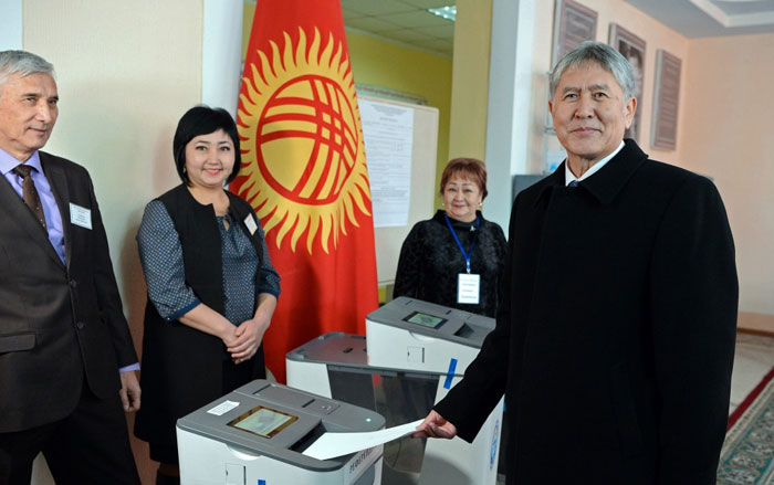 Kyrgyzstani President Almazbek Atambayev (right) poses for a photo as he inserts his ballot into a precinct count optical scan (PCOS) machine, a device that's crucial for automated electoral systems, during a referendum on Dec. 11, 2016. This system was test-operated in local elections in May 2015 and in the parliamentary election in October 2015.
