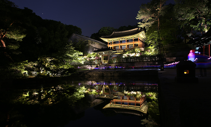 Participants in the Moonlight Tour of Changdeokgung Palace walk along the Buyongji Pond while holding traditional red and blue lanterns on April 30.