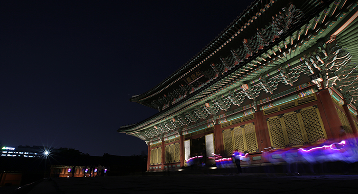 Participants in Changdeokgung Palace's Moonlight Tour walk around the Injeongjeon Hall while holding traditional red and blue lanterns on April 30.
