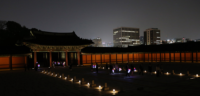 During the Moonlight Tour of Changdeokgung Palace, participants walk through the middle of the courtyard where the <i>pumgyeseok</i>, officials’ rank stones, stand, in front of the palace's Injeongjeon Hall on April 30.