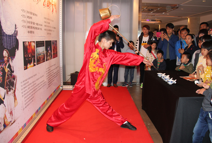 Before the opening ceremony on October 17, a Chinese performer (top) rides a unicycle as part of the performances going on in the lobby. Another performer shows his knack at pouring tea from a teapot with a long spout. 