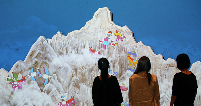 Staff at the Children’s Museum inspect the screen of the interactive video about traveling in ancient Korea.