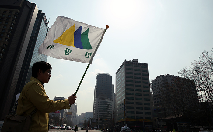 A man holds the civil defense drill flag as he participates in the nationwide drill near Seoul Plaza on March 14. (photo: Jeon Han)