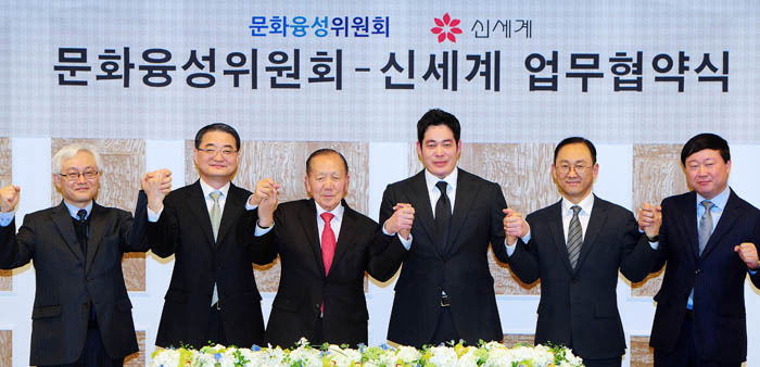 Chairman Kim Dong-ho of the Presidential Committee of Cultural Enrichment (third from left), Vice President Chung Yong-jin of Shinsegae (third from right) and other participants pose, hand-in-hand, after signing an agreement to boost the government's 