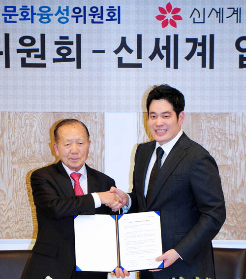 Chairman Kim Dong-ho of the Presidential Committee of Cultural Enrichment (left) and Vice President Chung Yong-jin of Shinsegae shake hands after striking an agreement to cooperate on enriching people's lives on March 18 at the Seoul Arts Center. (photo courtesy of Shinsegae)