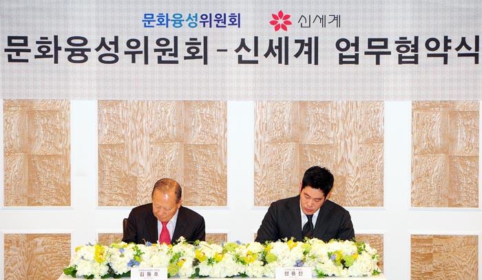 Chairman Kim Dong-ho of the Presidential Committee of Cultural Enrichment (left) and Vice President Chung Yong-jin of Shinsegae sign a joint agreement to boost the "Culture Day" campaign. (photo courtesy of Shinsegae)