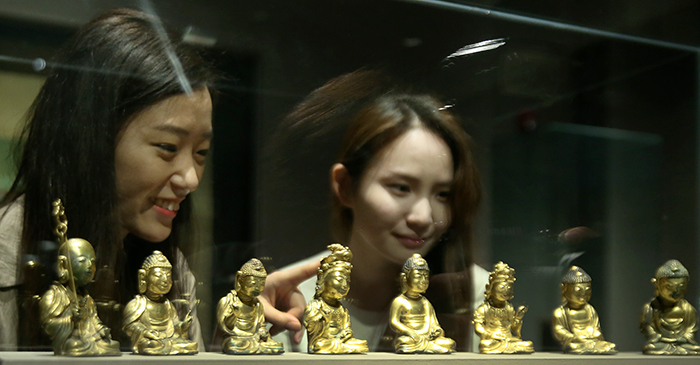 Visitors admire the miniature Buddha statues at the 'Devout Patrons of Buddhist Art' exhibit at the National Museum of Korea on May 22. 