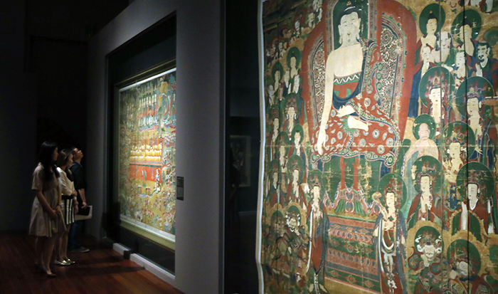  Visitors admire the 'Saving Hungry Ghosts by Giving Nectar' painting produced during Joseon times in 1764, part of the 'Devout Patrons of Buddhist Art' exhibit going on at the National Museum of Korea, on May 22. The painting on the right is the 'Shakyamuni's Preaching at Vulture Peak' painting, made in 1777 during Joseon times. 