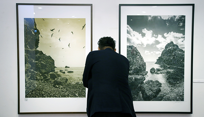 Photographer Kim Jung-man admires his photos on display at an exhibition in Seoul, on July 28. (photo: Jeon Han)