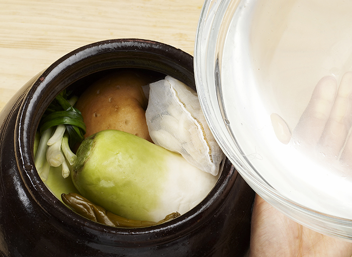 Put the salted white radish into a jar and add the remaining ingredients together. Pour the salted water. Place a heavy object on top of the ingredients to keep the Dongchimi immersed.