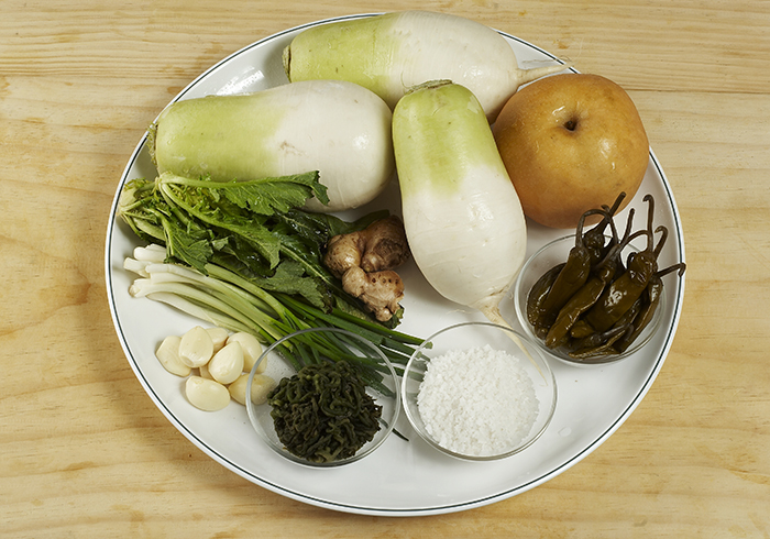 Main ingredients for dongchimi include white radish, salt, pear, green onion, garlic, ginger, and red pepper.