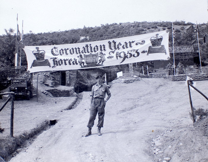 Signals Officer Gunner Doug Leyland poses under his painted banner in 1953. The banner says, "Coronation Year, Korea, 1953." (photo courtesy of the Korean Cultural Centre UK)