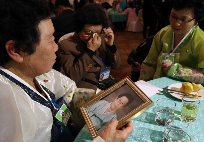 Kim Yong-ja (center), a 68-year-old South Korean woman, sheds tears while showing a photo of her mother to her younger sister, Kim Young-sil, from the North, during the family meetings. Her mother died a few days ahead of the meeting. (photo: Yonhap News)