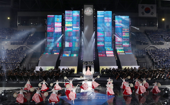 <i>Gugak</i> singer Song So-hee and a group of dancers perform in the ‘One Year to Go Ceremony’ at the Gangneung Hockey Center in Gangwon-do Province on Feb. 9. National flags of the participating nations are projected onto the background screen.