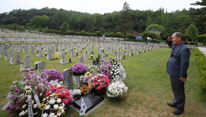 War veteran Oh Wan-gyu salutes the tomb of General Chae Myung-shin.