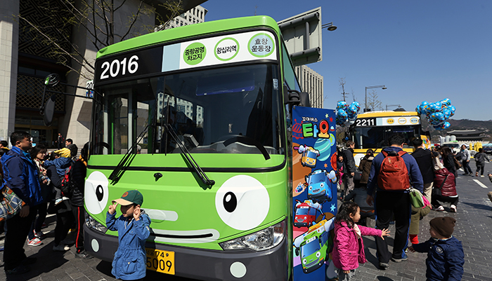 Children pose in front of Rogi, the green bus, one of the four main characters from “Tayo the Little Bus,” at Gwanghwamun Square in central Seoul on April 6. (photo: Jeon Han)