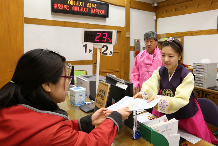 Public servants Kim Yeong-sin (center) and Nam Hee-sue (right) help a local resident while dressed in Hanbok at Hyehwa-dong Office, Jongno District in Seoul, on April 2 (photo by Jeon Han).
