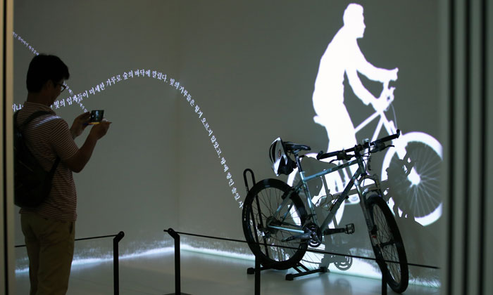 A museum-goer takes a photo of the bicycle that novelist Kim Hoon rode when he took a bicycle trip.