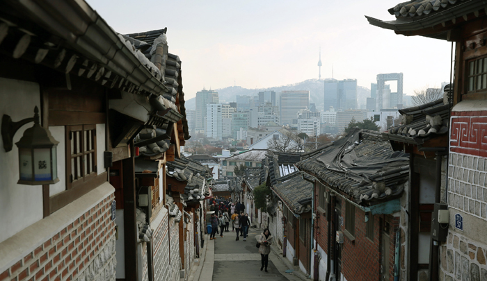 The Bukchon Hanok Village, a neighborhood of traditional Hanok residences in Jongno-gu, Seoul, creates a contrast between tradition and modernity, as it blends with the surrounding high-rises. The stark contrast attracts tourists not only from home, but from abroad, too. 