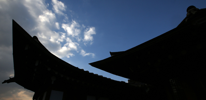 The cloudless clear sky is spread above and between Hanok roofs. 
