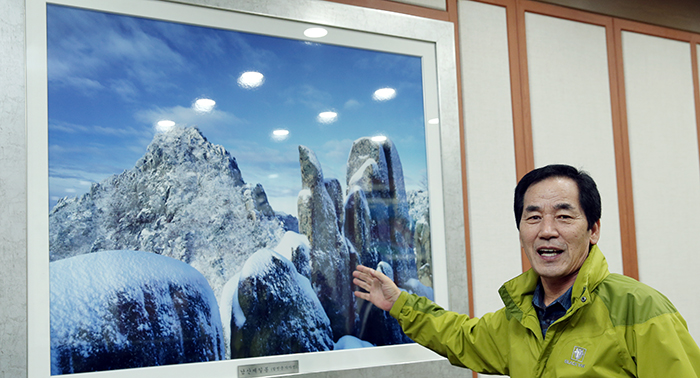 Chief of Hapcheon County Ha Chang-hwan gestures toward a picture of the heaven-sent natural beauty of Maehwasan Mountain.