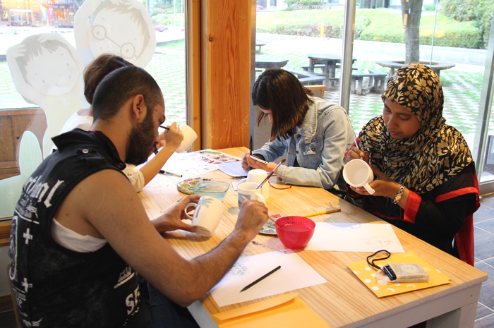 International students paint their bisque-fired mugs while learning about Korea's ceramic traditions at the Gyeonggi Ceramic Museum.