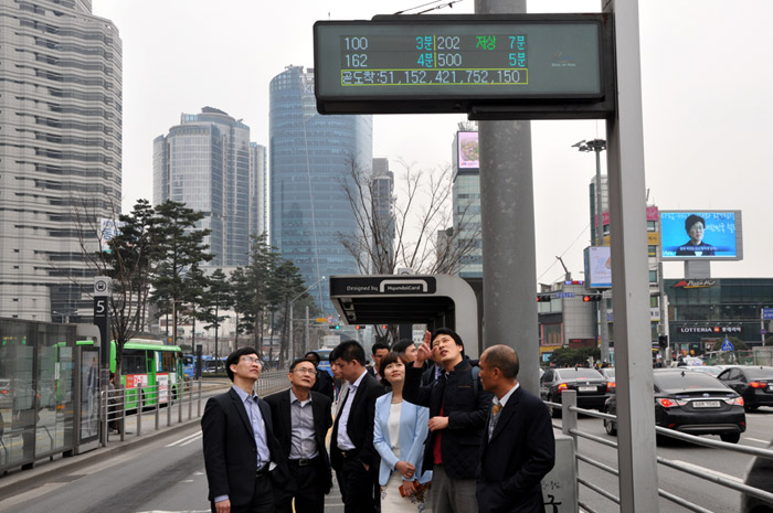 Vietnamese government officers look at a bus information signboard at a bus stop at Seoul Station to learn about public transport management systems in Korea. (photo by ITS Korea)