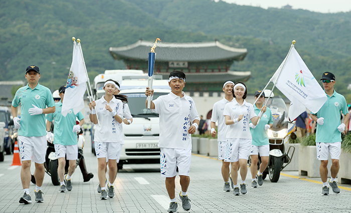 One of the torch bearers runs along Sejongdae-ro with Gwanghwamun as a backdrop, in Seoul on September 16.