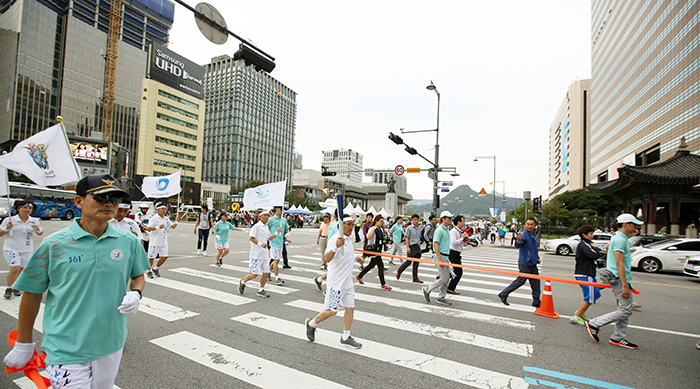 Participants in the torch relay for the Asian Games cross a street along Sejongdae-ro as they head toward Jongno on September 16.