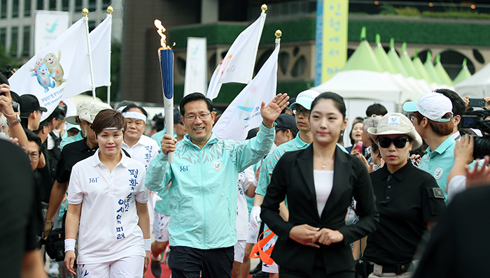 Torch bearer Park Seon-kyu, leader of the torch relay squad, arrives at Seoul Plaza alongside handball coach Lim Oh-kyung on September 16.