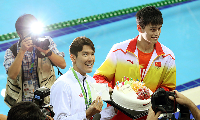 Park Tae-hwan (center) smiles as he receives a birthday cake from Sun Yang, a rival Chinese swimmer, on September 26, one day before his actual birthday.