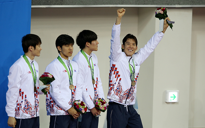 Park Tae-hwan (right) raises his arms to the crowd on September 26 after winning bronze in the 4x100 meter freestyle relay, as he becomes the most decorated Korean athlete at the Asian Games.