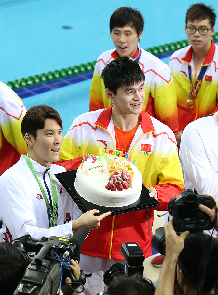 Park Tae-hwan (left) poses for a photo with Sun Yang as he receives a birthday cake from his mainland Chinese competitor on September 26.