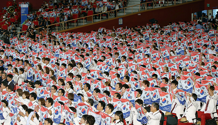 Korean athletes cheer for their team, holding aloft their Taegeukgi national flag scarves, during the launch ceremony for Team Korea on September 11.