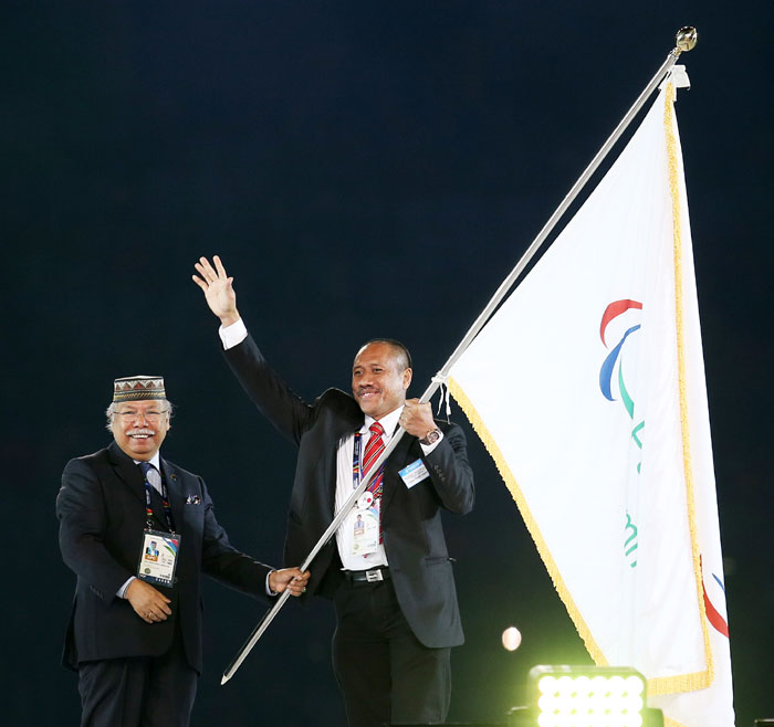 A representative from Indonesia waves after receiving the official flag of the games from President of the Asian Paralympic Committee Datuk Zainal Abu Zarin.