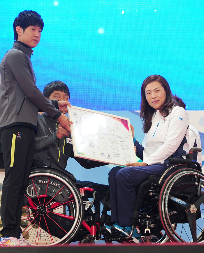 Young athletes offer a plaque with messages of encouragement to the nation's wheelchair athletes during the Team Korea launch ceremony.